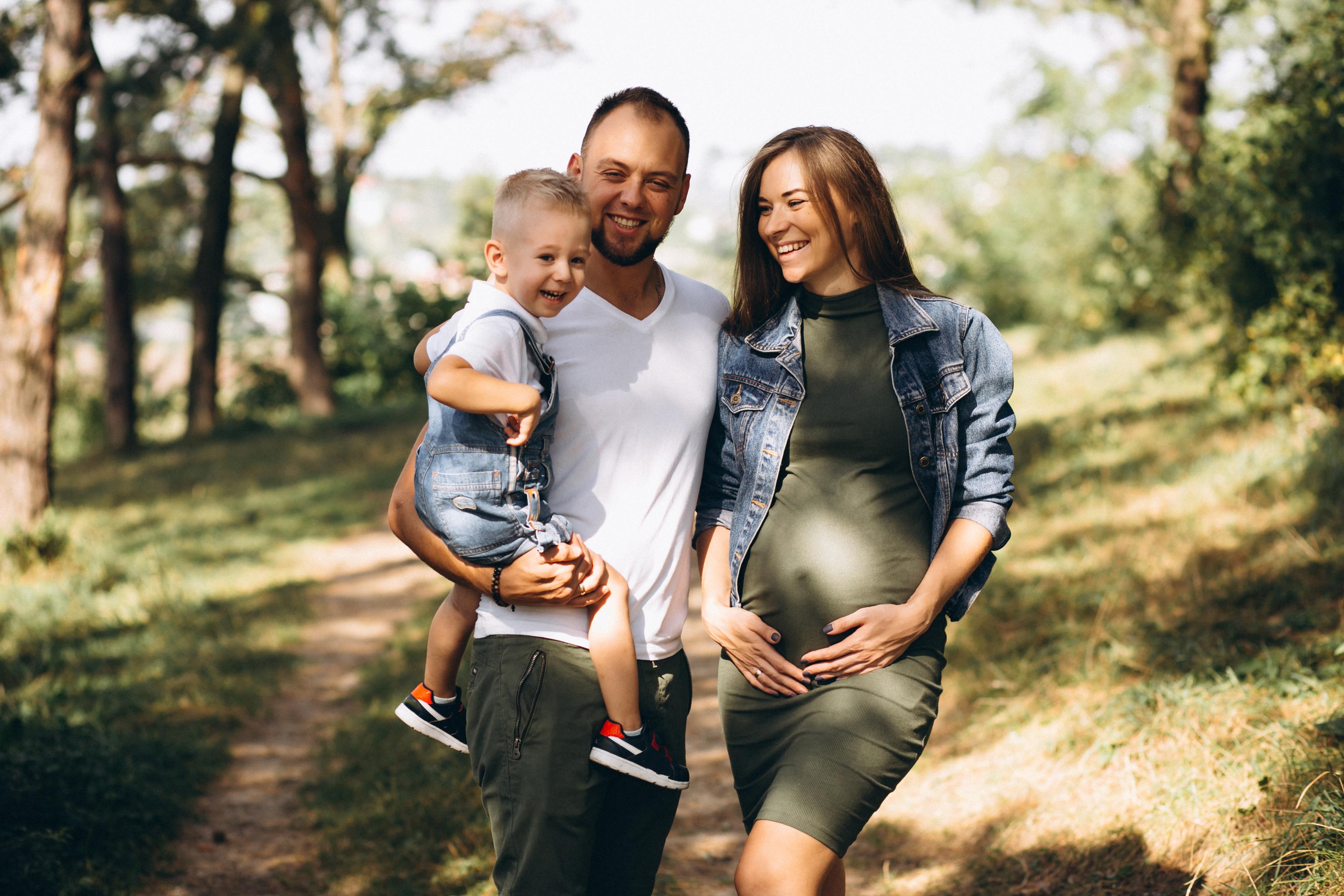 A happy family expecting a baby, walking outdoors
